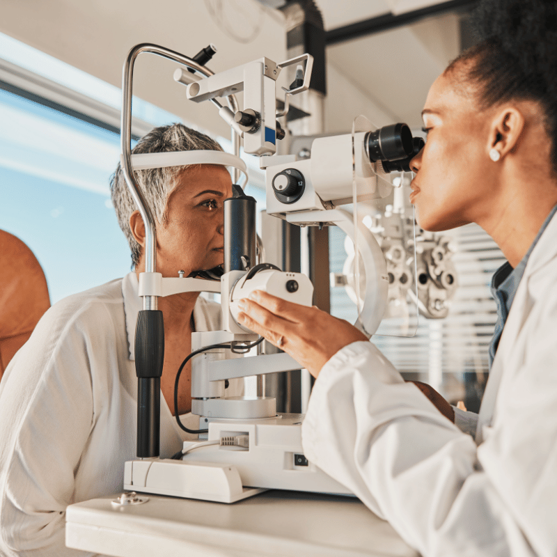 Optometry technician looking at a senior woman's eyes