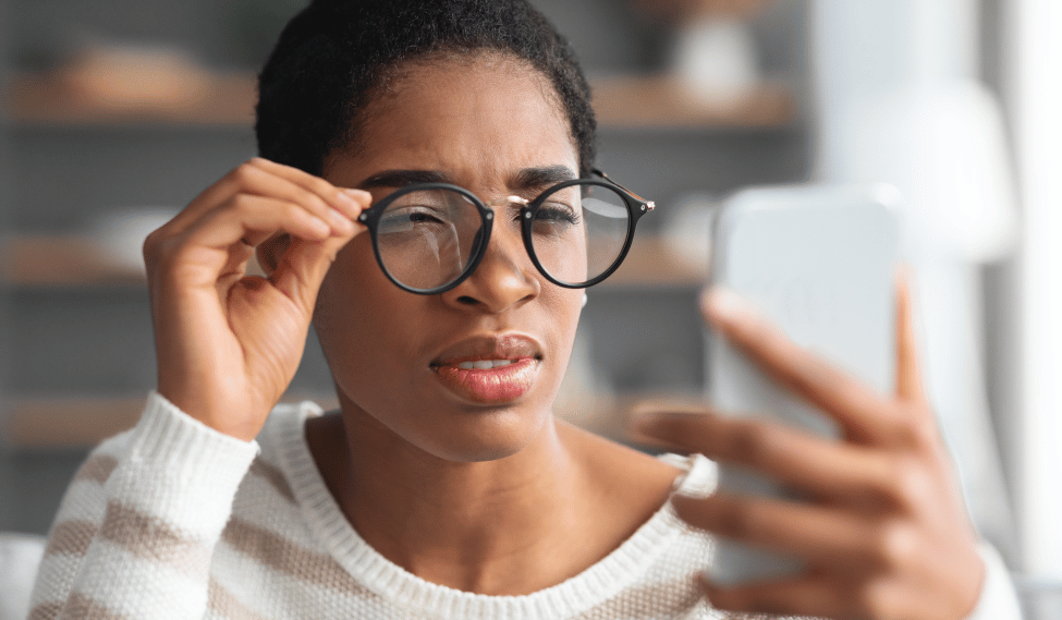 Black female wearing glasses and squinting at phone