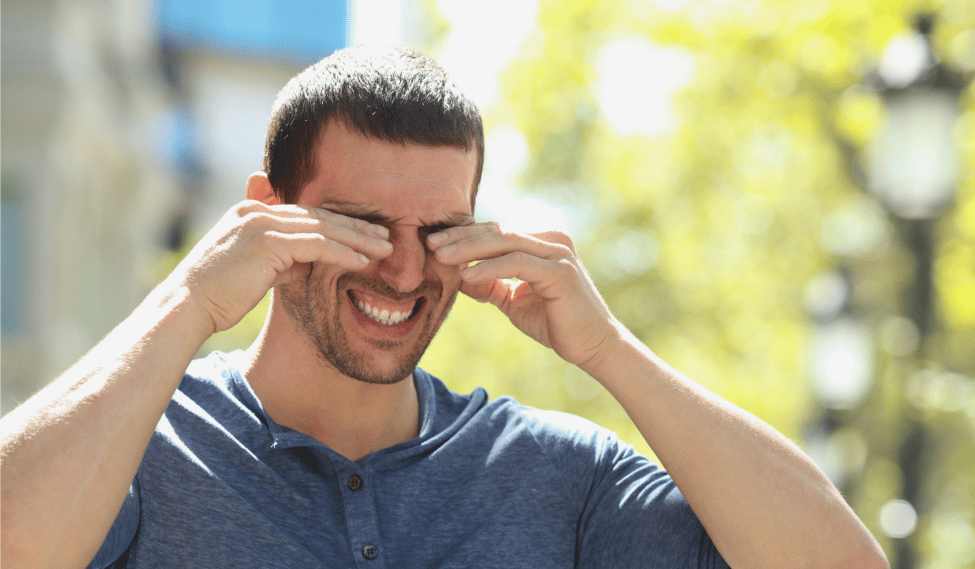 Man itching his eyes while outdoors