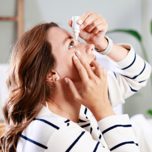 Young woman putting eye drops in her eyes