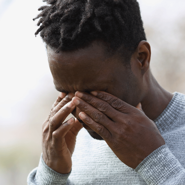 Black man rubbing his eyes