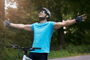 Man riding a bicycle outside while wearing a helmet and sunglasses