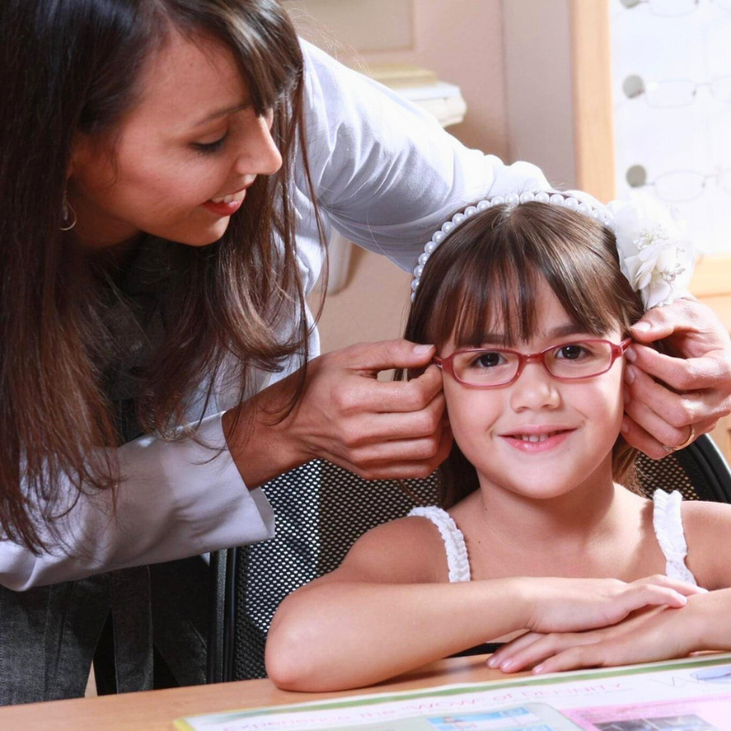 Magaly Murray helping a child fit glasses