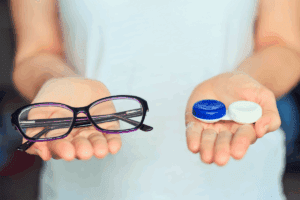 Woman holding glasses in one hand and a contact lens case in the other