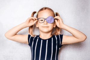 Young girl wearing glasses with an eye patch over one side