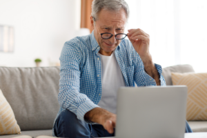 Senior man squinting through his glasses at his laptop