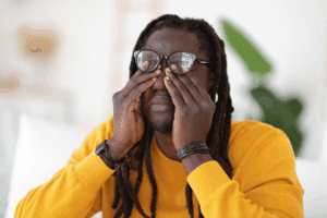 Black man rubbing his eyes