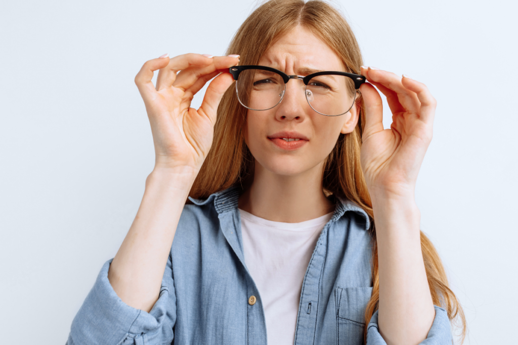 Young woman squinting through the lenses on a pair of glasses