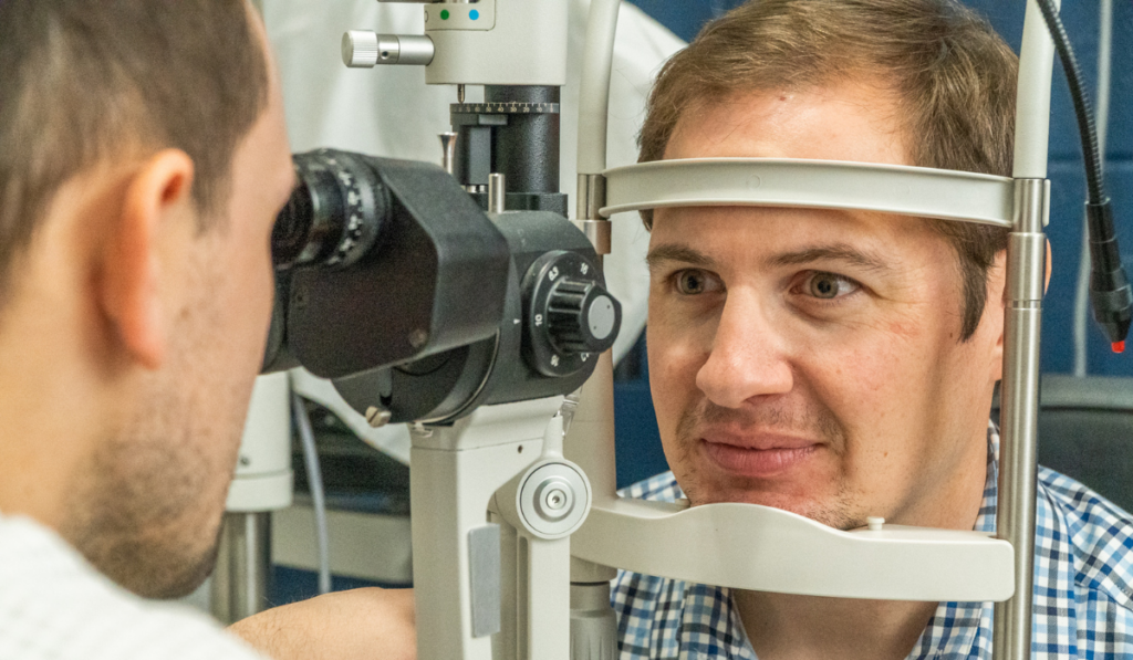 Dr. Ball looking at a patient's eyes with a slit lamp during eye exam