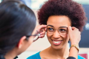 Optician fitting glasses on female patient