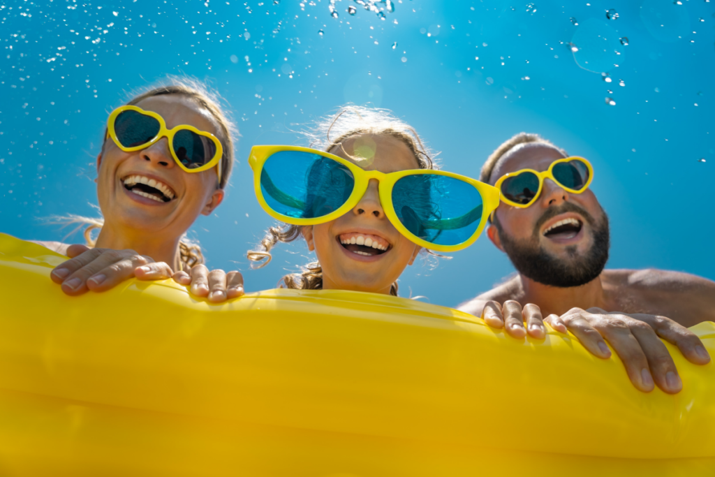 Mom, dad, and daughter wearing big sunglasses and holding onto a pool float