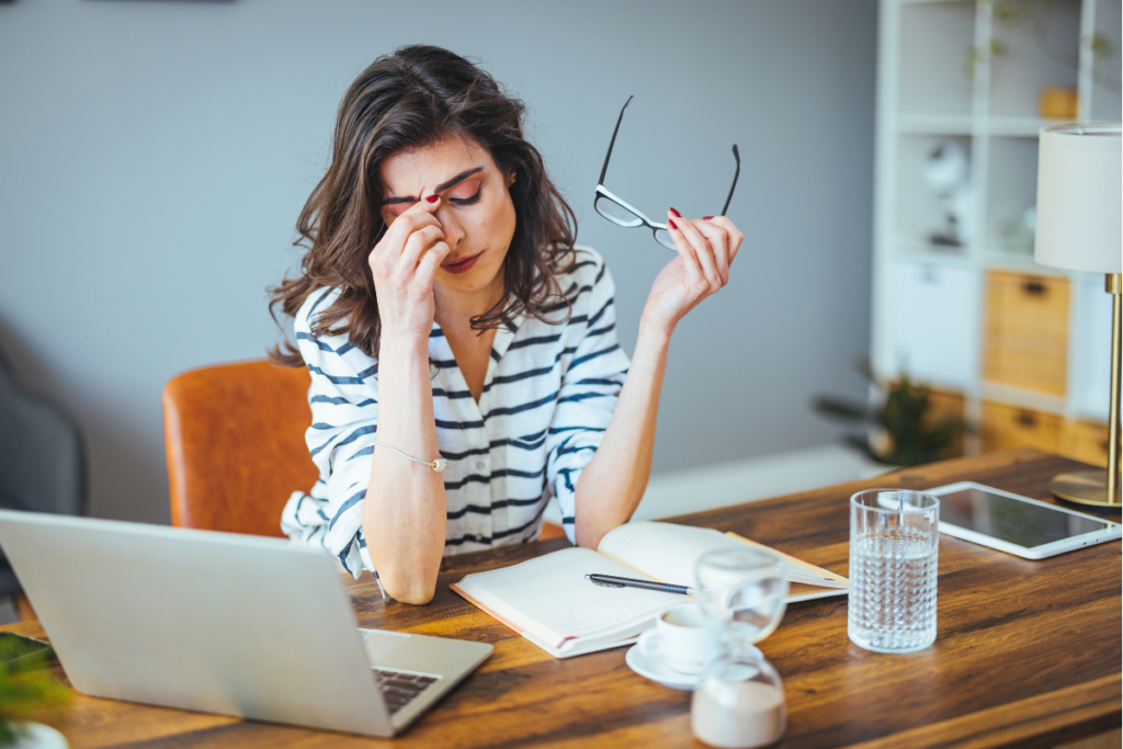 Stressed woman rubbing her eyes in a home office