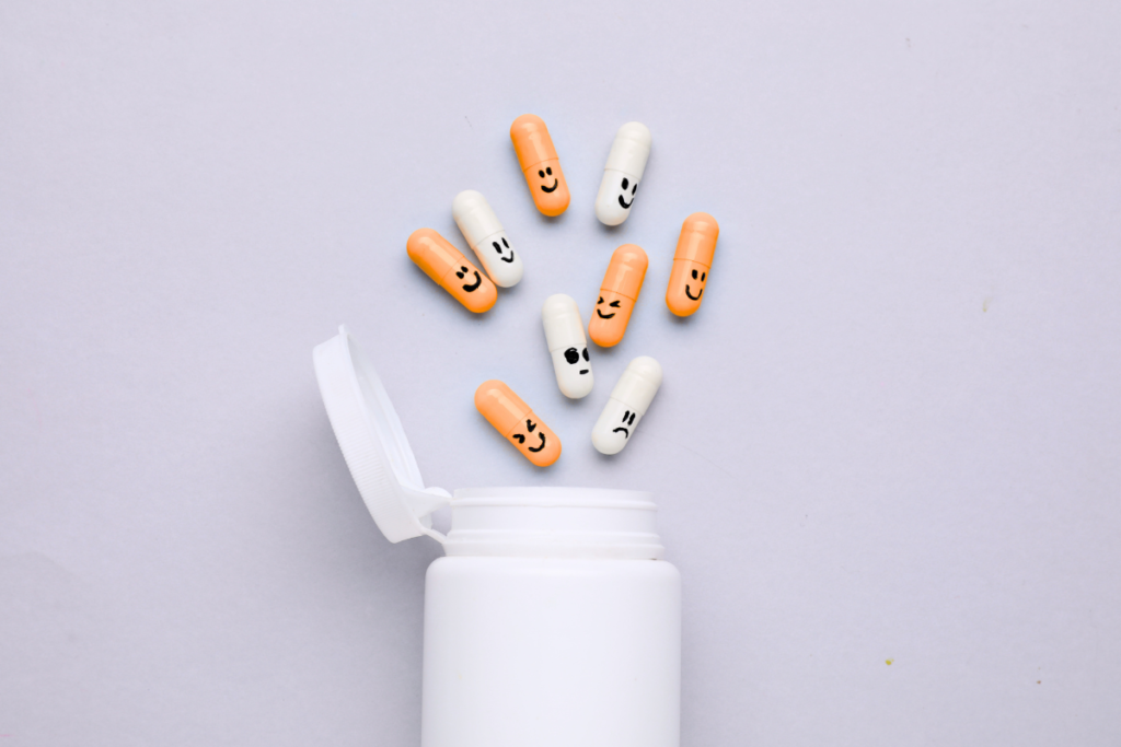 Medication bottle with orange pills with hand-drawn faces spilling out